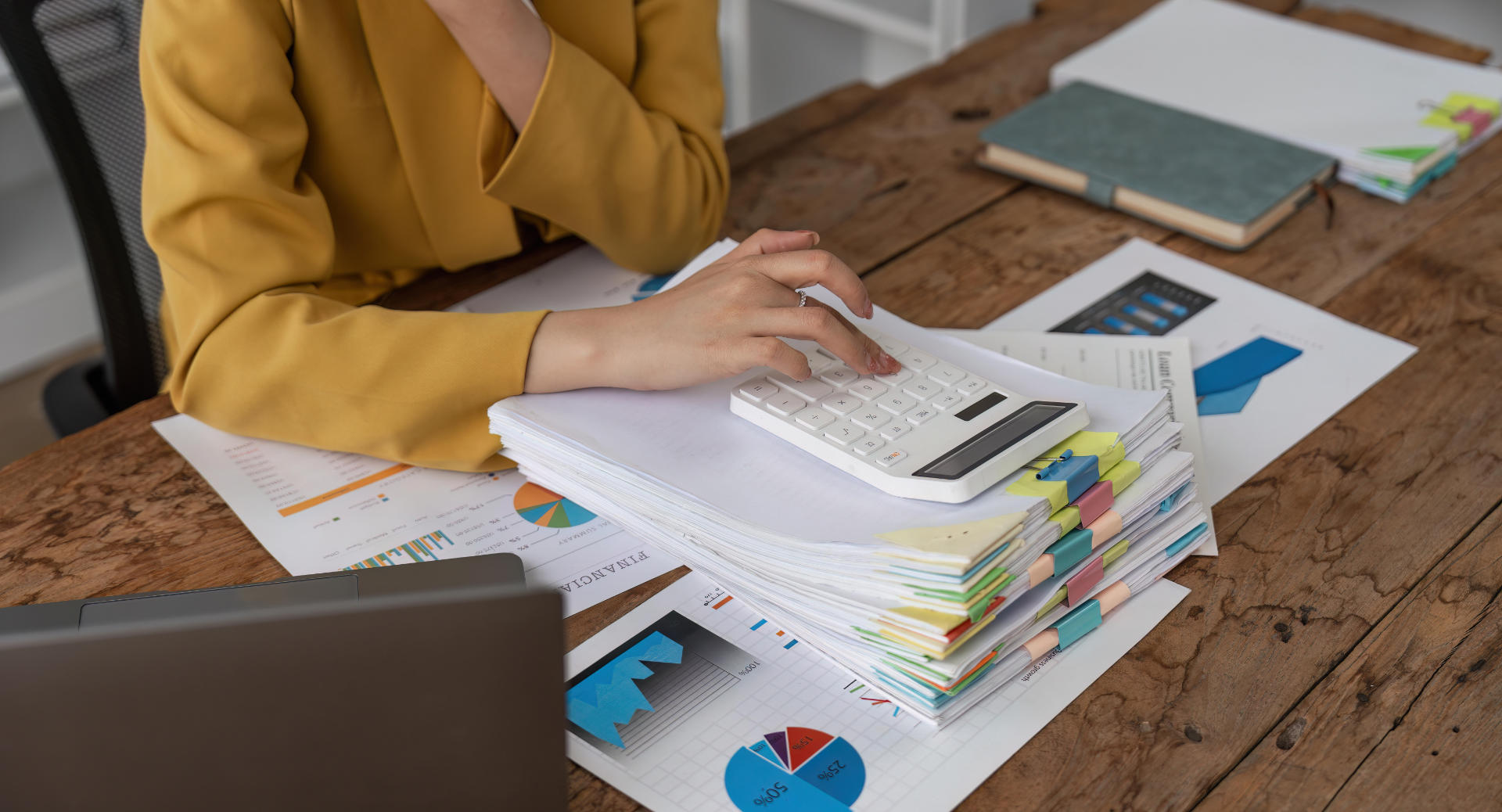 Close up of businesswoman hands using a calculator to check company finances and earnings and budget. Business woman calculating monthly expenses, managing budget, papers, loan documents, invoices