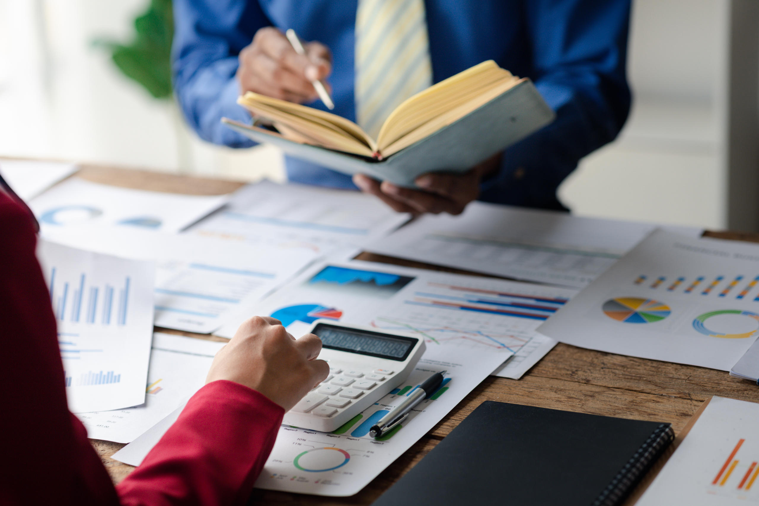 Two businessmen are reviewing monthly sales documents for analys