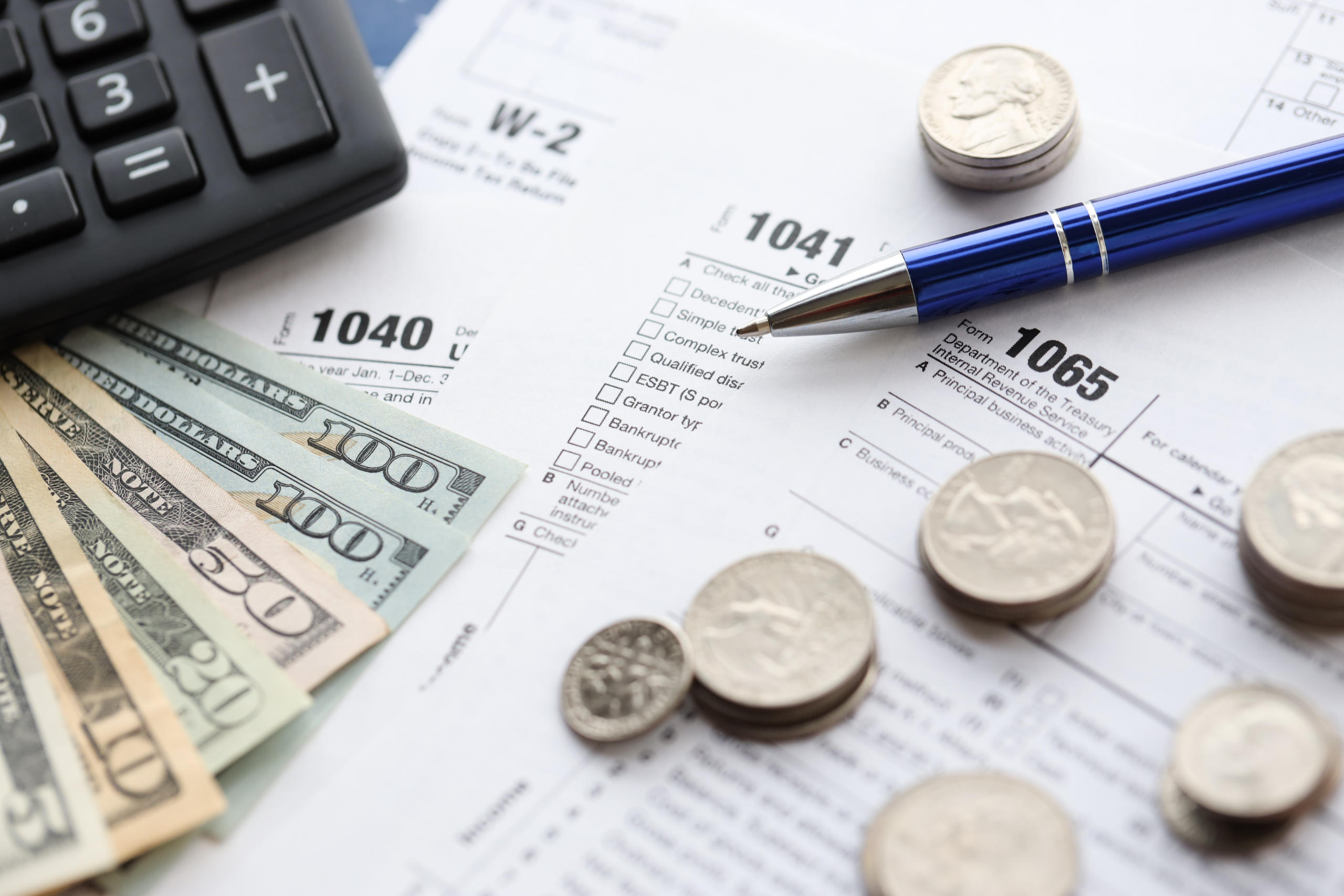 American US dollars money bills and coins with pen and calculator on IRS tax form blanks
